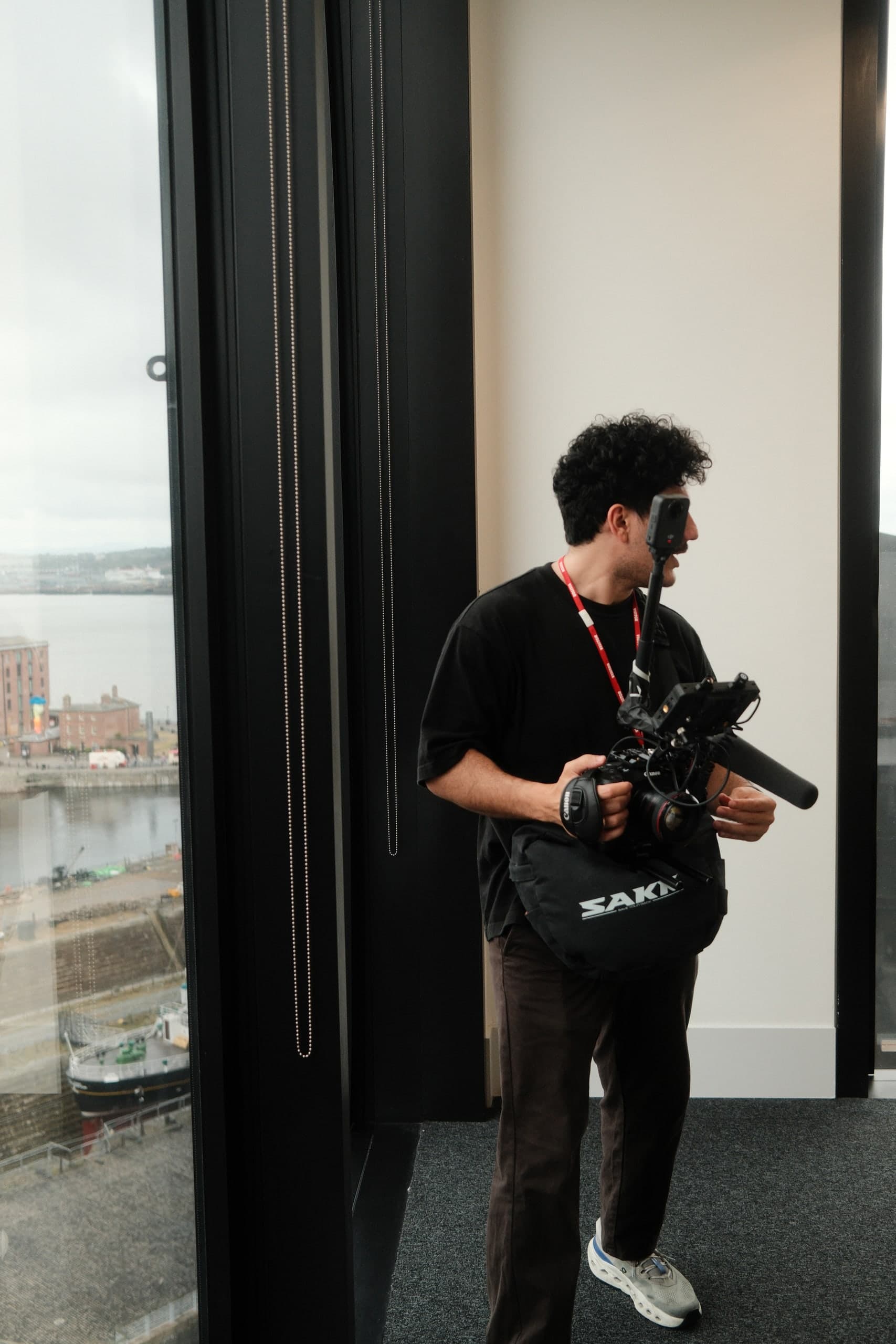 A camera operator by a window over the river